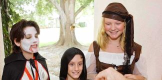 Children in Halloween costumes collecting candy from a house