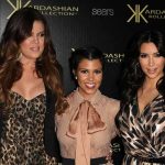 Three Kardashian sisters posing together at a fashion event