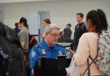 $10,000 Bonuses IGNITE Airport Uproar TSA agent checks passengers documents at airport security.