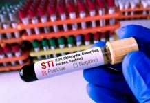 Millions at Risk – AIDS Prevention Efforts Vanish Overnight Gloved hand holding STI test tube labeled Negative.