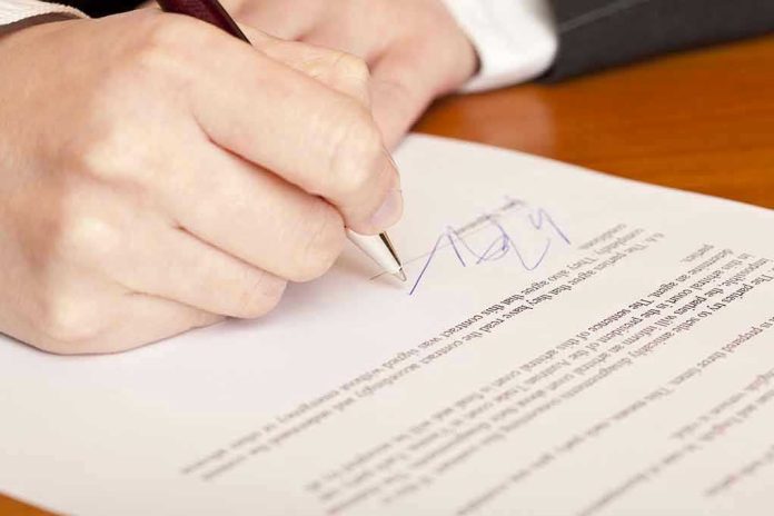 66092728 Hand signing a document with a pen.