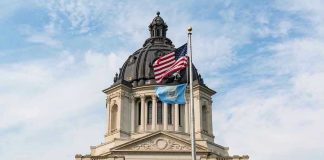 Building with dome and flags flying outside.