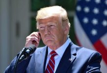 Trump Pardoned Convict ARRESTED AGAIN – Faces New Charges Man in a suit adjusting an earpiece.