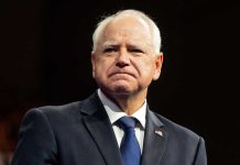 Somali Gang Mocks American Taxpayers Amid Fraud Scandal Man in suit with a U.S. flag pin.