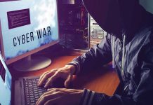 Hacker typing at desk with Cyber War screen.