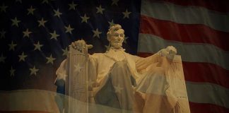 Statue of Abraham Lincoln seated against a backdrop of the American flag
