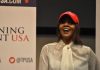 Candace Owens, Erika Kirk Feud ERUPTS – Private Meeting Held A woman wearing a red cap and a white blouse speaking at a political event