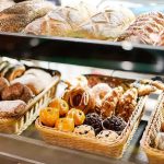 A display case filled with various types of baked goods including breads and pastries