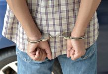 Terrifying Abduction Thwarted by Dad’s Quick Thinking A person in handcuffs viewed from behind, wearing a plaid shirt and denim jeans