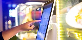 A hand interacting with a touchscreen menu in a restaurant