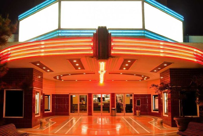 Entrance of a vintage movie theater illuminated by neon lights at night