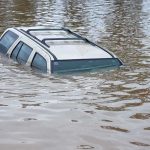 A partially submerged vehicle in floodwaters