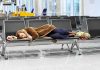Major Airport COLLAPSES – Thousands Stranded Instantly A traveler sleeping on a bench in an airport waiting area