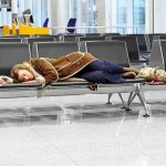 Major Airport COLLAPSES – Thousands Stranded Instantly A traveler sleeping on a bench in an airport waiting area