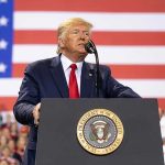 Trump HALTS Childcare Funding Sparking Legal Chaos Man speaks at podium with U.S. flag background.