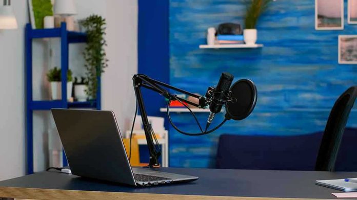 Laptop and a microphone on a desk.
