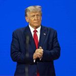 Outrage Erupts: Trump Targets Blue States Over Daycare Fraud Man in a suit with a blue background.