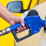 Pump Prices SPIKE—Middle East Chaos Deepens A person refueling a car at a gas station with a blue nozzle