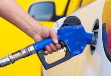 A person refueling a car at a gas station with a blue nozzle