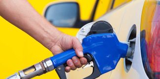 A person refueling a car at a gas station with a blue nozzle