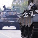 Tanks on a road with soldiers inside.