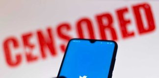 Phone displaying Twitter app with CENSORED in background.