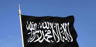 Black flag featuring Arabic script against a blue sky