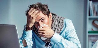 Cruise Passengers Carrying RARE Killer Disease Home Man with tissue feeling unwell at laptop desk