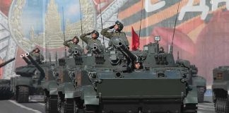 Tanks with military personnel in street parade formation.