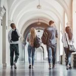 College Is A Scam? Viral Clip Sparks Outrage Four students walking in a corridor together.