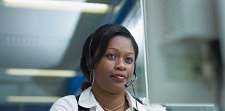 A woman wearing a headset, focused on her work at a computer in an office setting