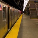 Subway station platform with train and exit stairs.