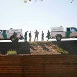 Border Patrol vehicles and agents on a ridge.