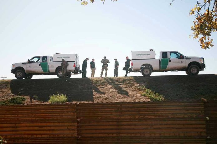 1243518340 Border Patrol vehicles and agents on a ridge.