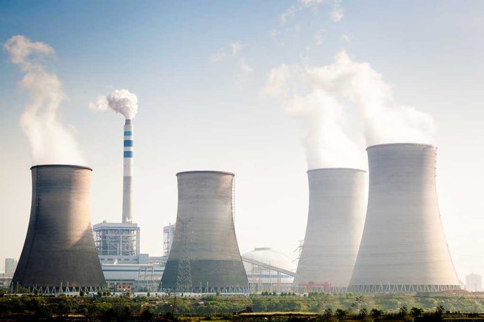 164603351 Four cooling towers of a power plant emitting steam.