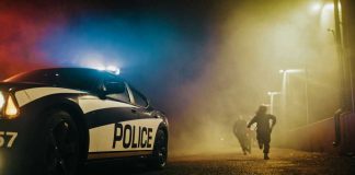 Police car with sirens next to running officers
