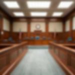 Empty courthouse courtroom with wooden benches and chairs.