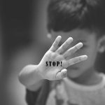 Child holding up hand with STOP! written on palm.