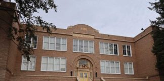 Historic brick school building with arched entrance and large white-framed windows