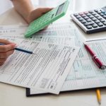 Shocking Spend: Data Missing, Money Flows Person calculating financial figures with documents and a calculator