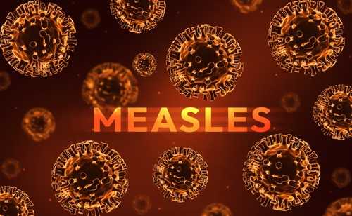 shutterstock_2591304911 Illustration of measles virus particles with the word 'MEASLES' in bold