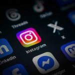 Close-up of a smartphone screen displaying various social media app icons, including Instagram