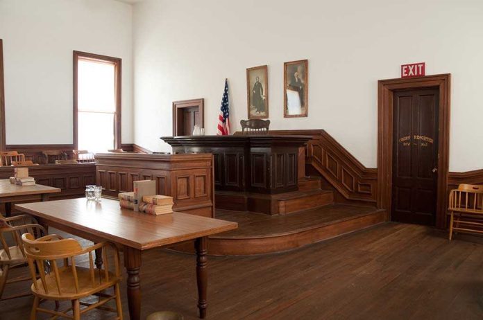 shutterstock_71233234-1 Interior of a historic courtroom with wooden furniture and an American flag