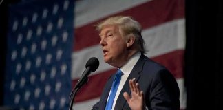 Trump Ally Upends Colombia — Now What? man in suit speaking at a podium with a US flag backdrop