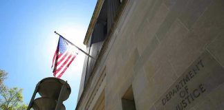 Guard Gunned Down Near White House — Now What? American flag at Department of Justice building exterior.