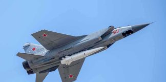 NORAD Jets Roar Over Final fighter jet with missile flying against a clear blue sky