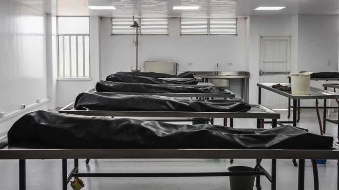 shutterstock_1442207993 Mortuary room with covered bodies on metal gurneys