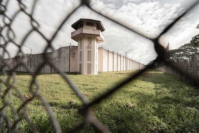 shutterstock_1587239341 Prison watchtower behind chain-link fence