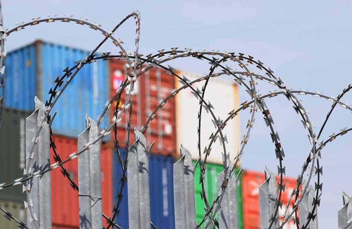 shutterstock_1377286811 Razor wire fence in front of stacked shipping containers