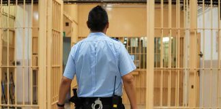 Medical Plea Rejected — Sudden Death Follows corrections officer walking through prison corridor